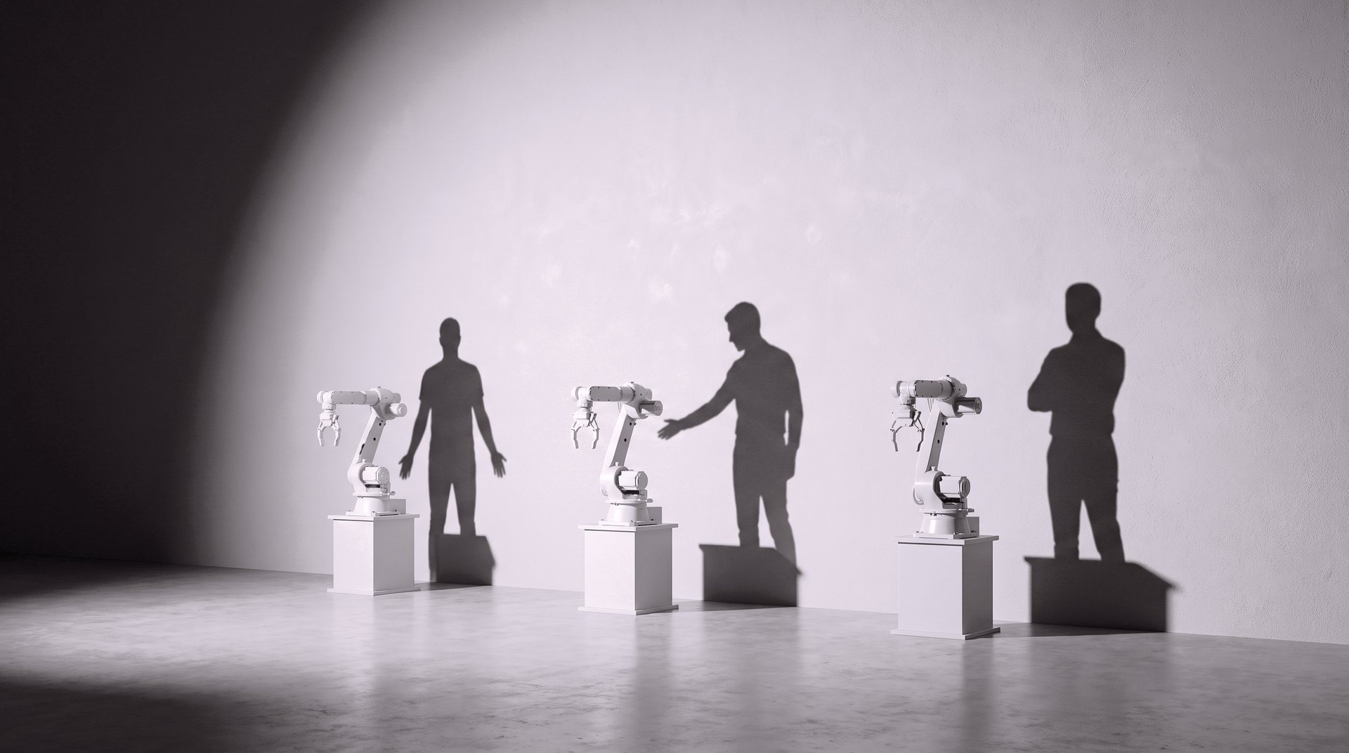 Three white robot arms on plinths along a sunlit wall, each with the shadow of a person standing beside it.